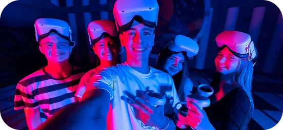 Grupa przyjaciół w goglach VR uśmiecha się do selfie przed sesją gier w wirtualnej rzeczywistości.